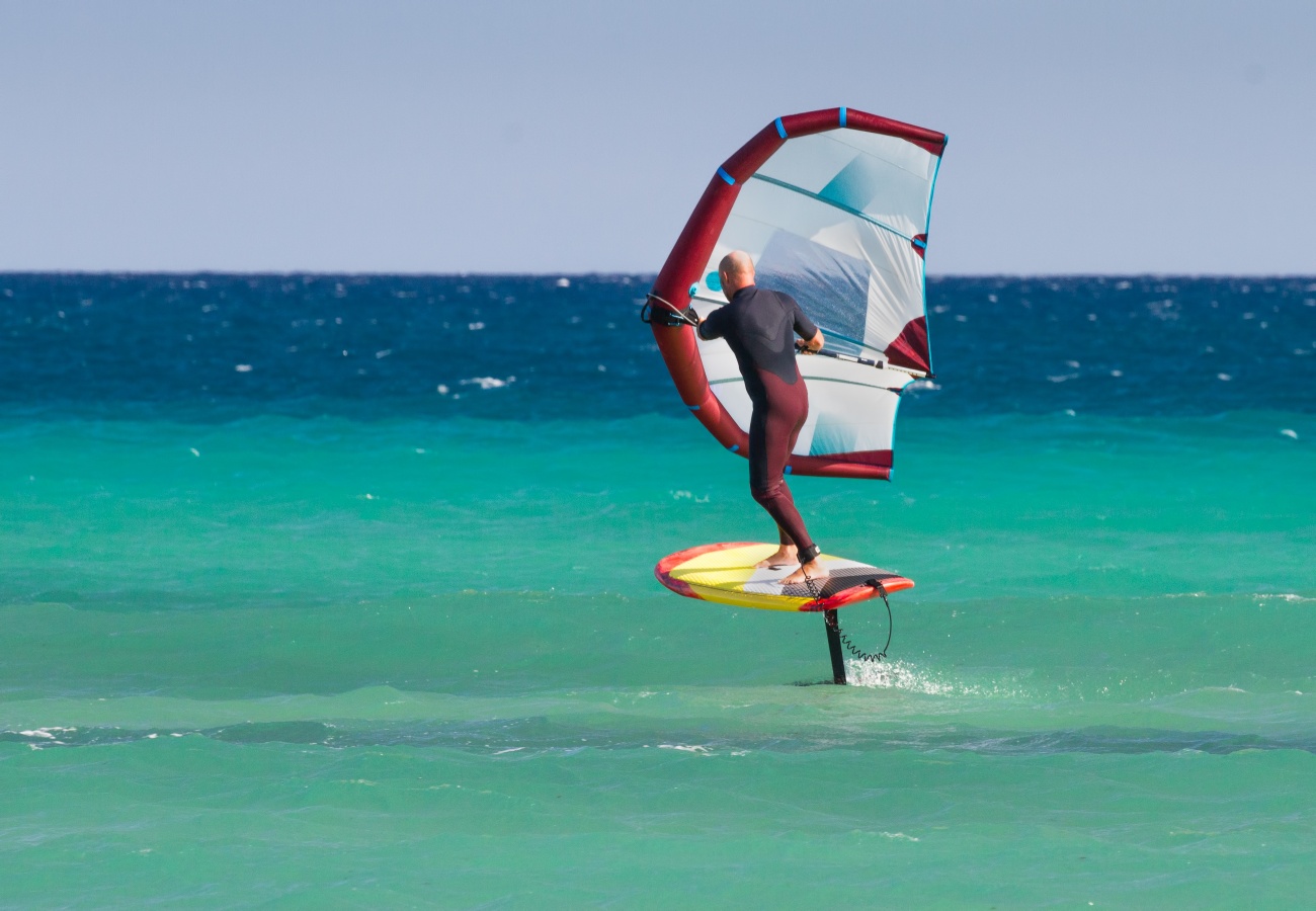 Rideur en wingfoil tenant son aile gonflable