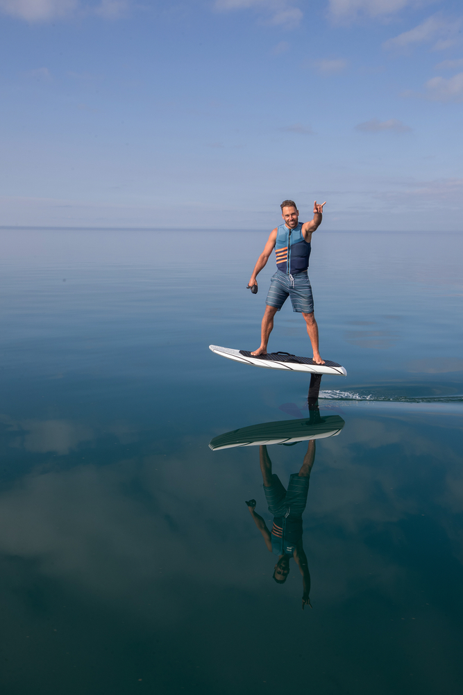Rideur en eFoil avec gilet de sauvetage au-dessus d’une eau calme