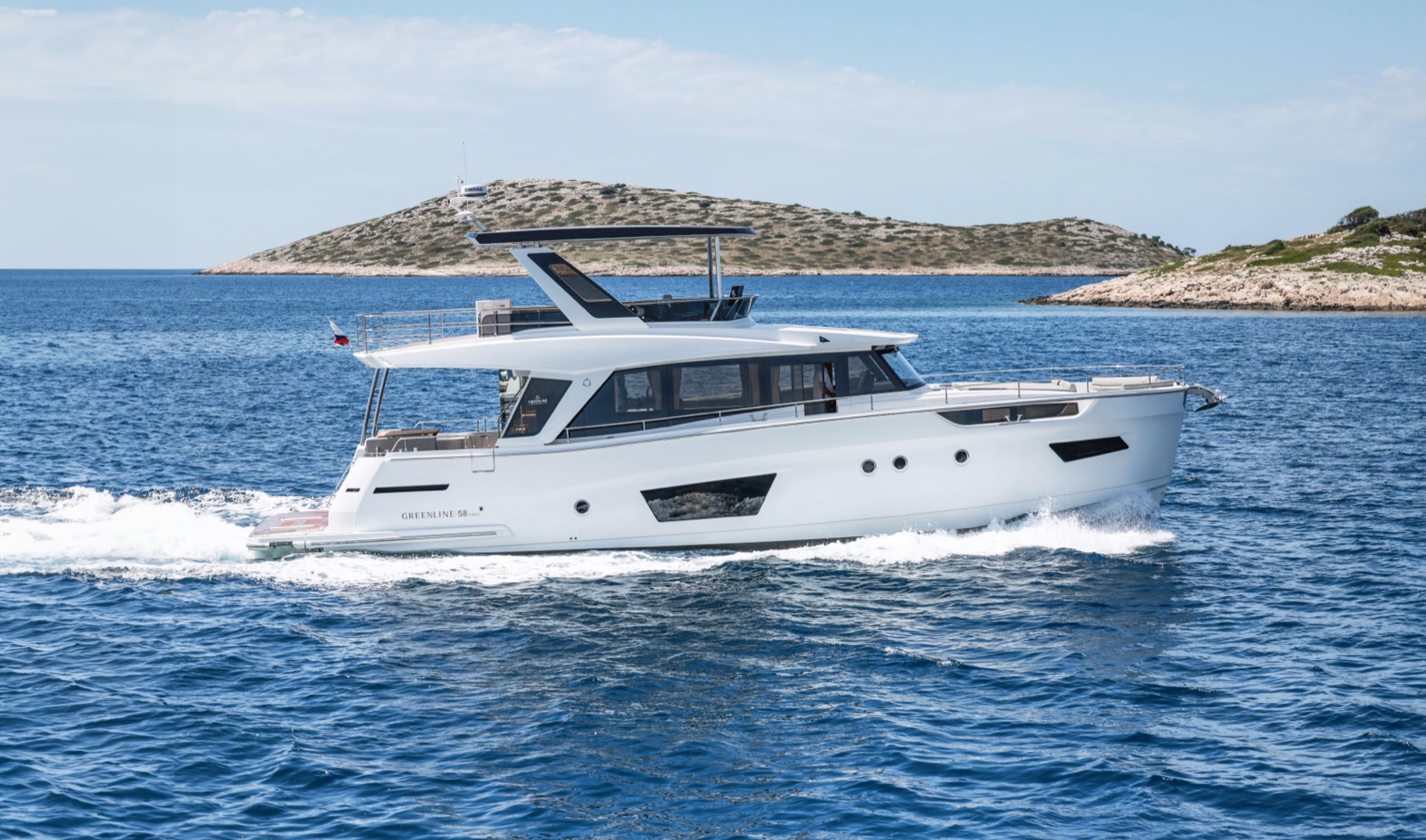The Greenline 58 Fly hybrid yacht seen from the side, with an island behind it